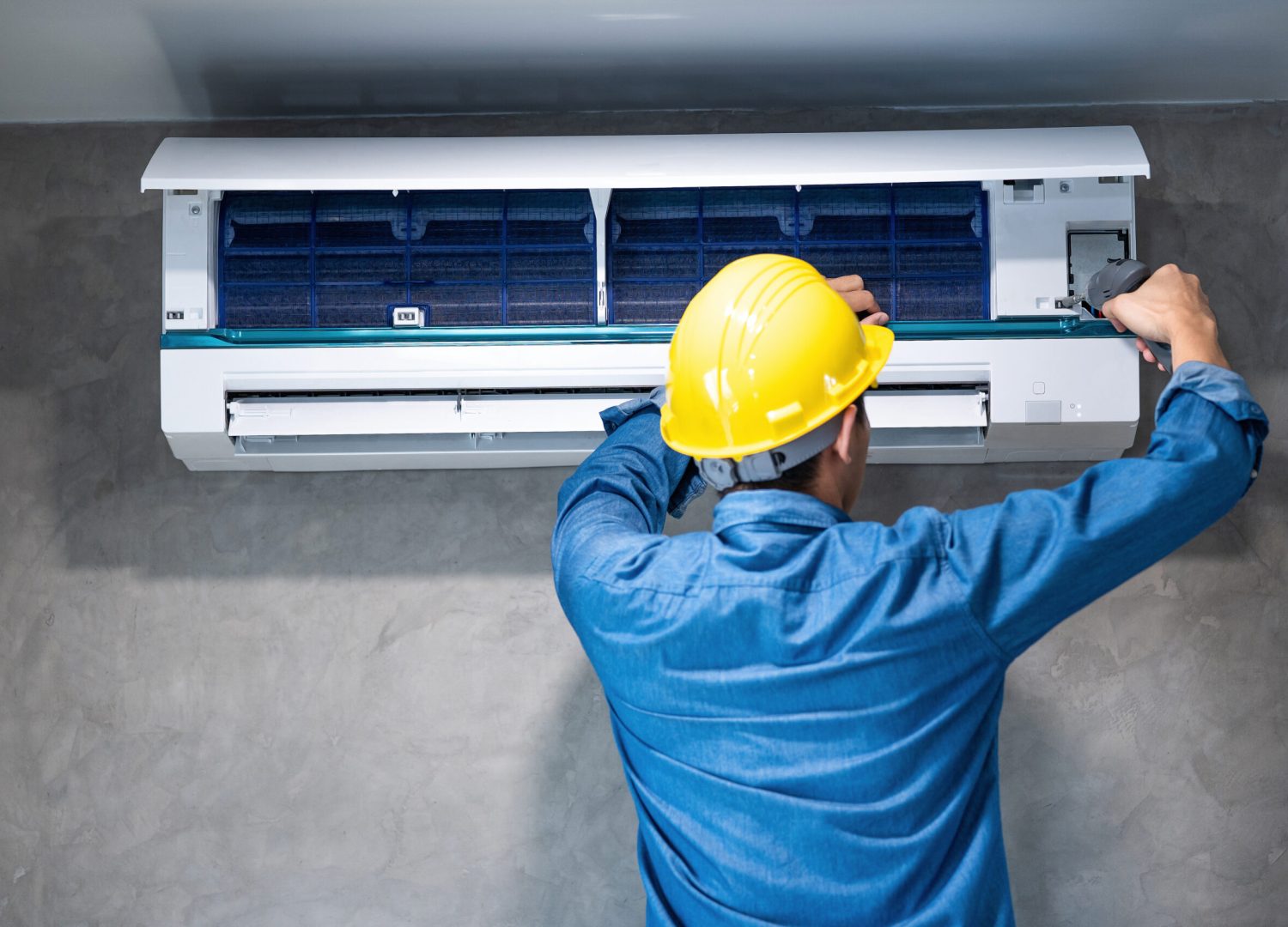 Technician man repairing ,cleaning and maintenance Air conditioner on the wall with screw driver in bedroom or office room.On site home service,Business ,Industrial concept.